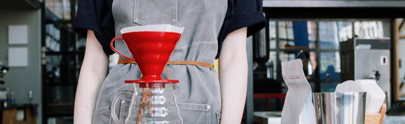 Processo de extração de café pelo método Hario V60 em um cone vermelho sobre uma jarra